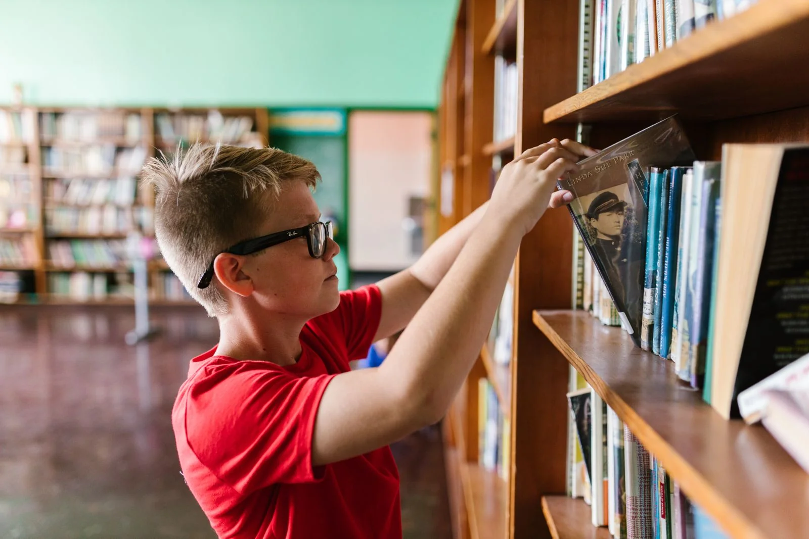 Jongen pakt een boek uit een boekenkast